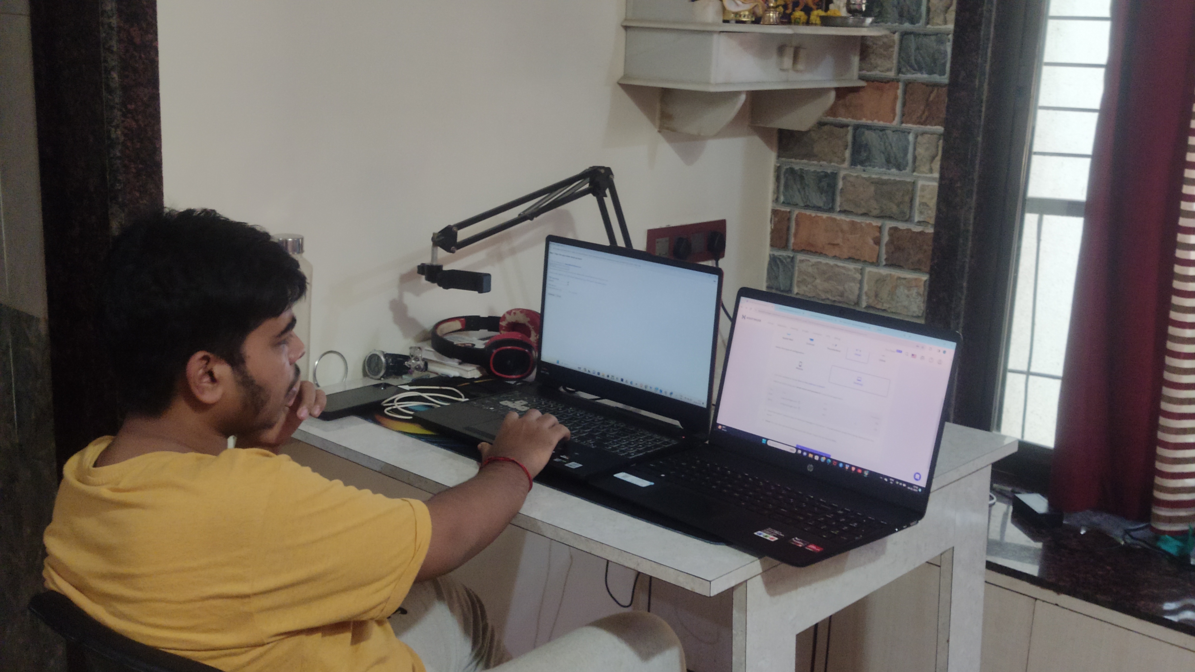 Deepak working at his desk with two laptops